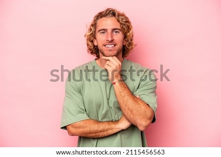 Young caucasian man isolated on pink background smiling happy and confident, touching chin with hand.