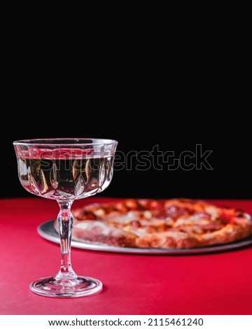 Glass of whiskey or other alcohol liquor served in a glass over red background with pizza. Vintage glass of hard liquor. Copy space vertical banner.