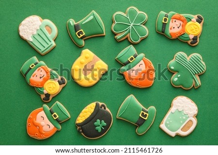 Different tasty gingerbread cookies for St. Patrick's Day celebration on green background