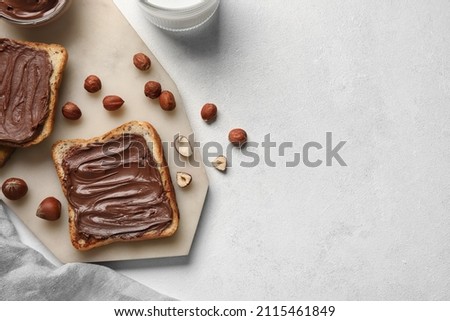 Board of bread with chocolate paste and hazelnuts on white background, closeup Royalty-Free Stock Photo #2115461849