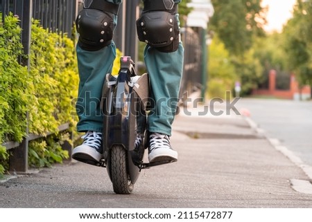 Rider's legs in protective gear on an electric unicycle (EUC). Driving around the city on an electric monowheel. Royalty-Free Stock Photo #2115472877