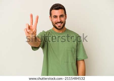 Young caucasian man isolated on white background showing victory sign and smiling broadly. Royalty-Free Stock Photo #2115484532