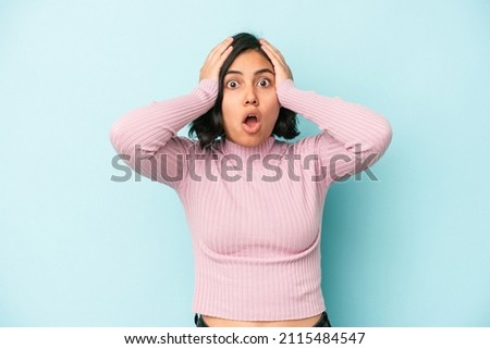 Young latin woman isolated on blue background being shocked, she has remembered important meeting.