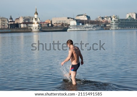 Caucasian hardened man while swimming in a pond in the cool season
