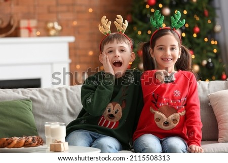 Happy little children watching TV at home on Christmas eve