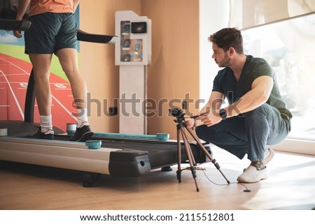 An orthopedist analyzing the biomechanical footprint study of an athlete while running on a treadmill.biomechanical study of foot drop Royalty-Free Stock Photo #2115512801