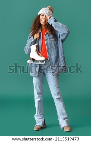 Happy young woman in winter clothes and with ice skates on color background