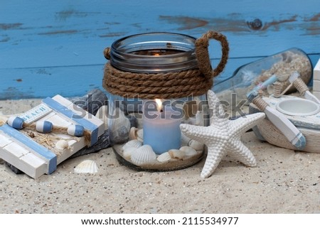 Maritime decoration with a candle, starfish and shells in the sand. Royalty-Free Stock Photo #2115534977