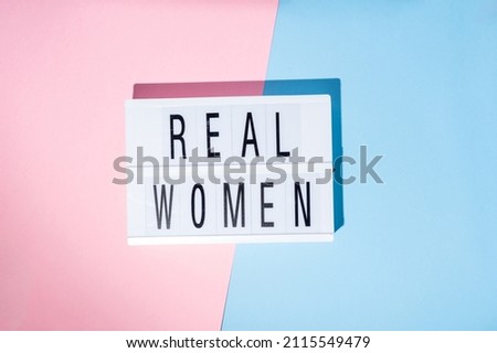 Real Women text on the lightbox. Concept of feminism on a blue and pink background. Top view