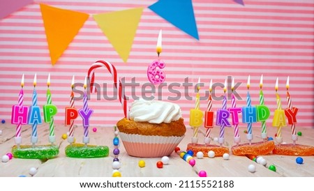 Happy birthday card to a child of six years old on a pink background, with a number in a cupcake. Beautiful happy birthday background with number 6 with burning candle. Festive background with colorfu
