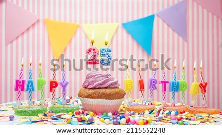 Happy birthday number 25. On a pink background, congratulations on the birthday of twenty-five years old. Muffins with pink cream with a burning candle. Copy space