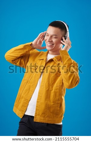 Portrait of happy young man enjoying good music in his headphones and dancing
