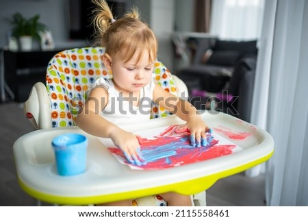 Cute little girl painting with fingers at home. Creative games for kids. Stay at home entertainment. High quality photo