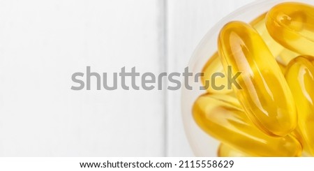 Omega-3 yellow capsules in a plastic scoop, nutritional supplements, close-up, top view.