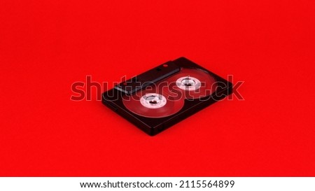 One black audio cassette on a red background