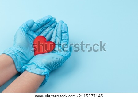 Female medicine doctor hands holding and covering red toy heart closeup. Cardiology concept.