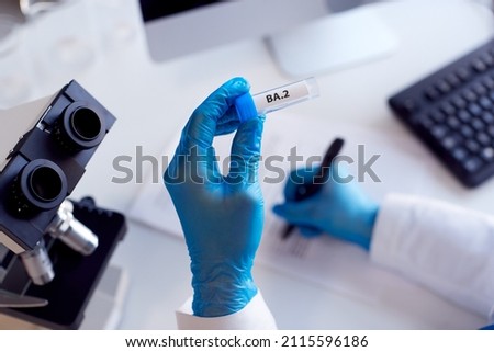 Close Up Of Female Lab Worker Wearing PPE Researching BA.2 Variant Of Covid-19 With Microscope Royalty-Free Stock Photo #2115596186