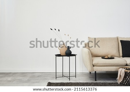 Minimalist living room interior design with beige sofa, creative metal side table and modern home accessories. Wallpaper. Copy space. Template.   Royalty-Free Stock Photo #2115613376