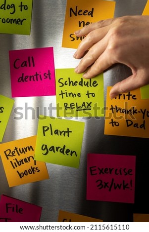 Hand Holding Schedule Time to Relax Sticky Note Memo to Fridge Door Full of Colorful Reminders