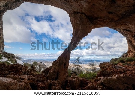 Bolumini cave from the inside, in the background a snowy landscape with blue sky. Mariola natural park ,Agres, Alicante, Spain.