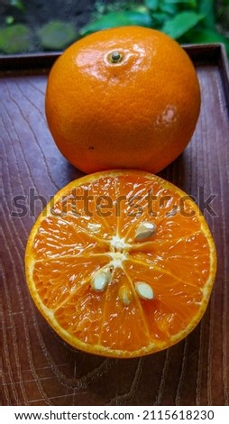 Orange with cut in half and green leaves isolated on wood plate background.
