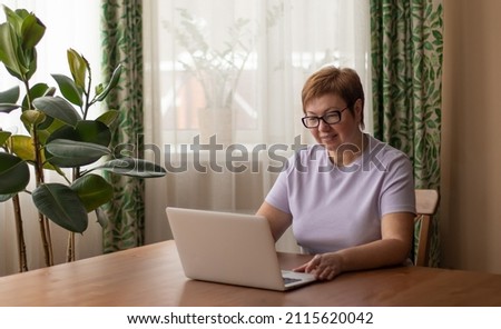 An elderly woman is working on a laptop. Elderly people and modern technology concept. 