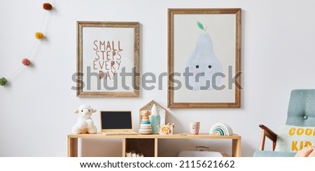 Cozy interior of child room with mint armchair, brown mock up poster frame, toys, teddy bear, dolls, plush animal, decoration. White wall. Warm kid space. Template.