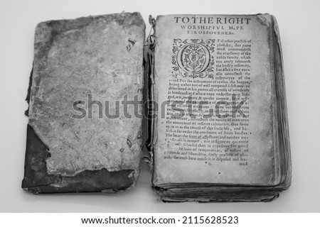 A Tattered Ancient English Book Sits Open.  Royalty-Free Stock Photo #2115628523