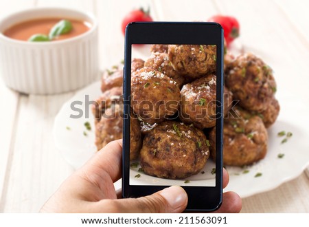 Man shooting with his cell phone camera meat balls.Selective focus on the phone