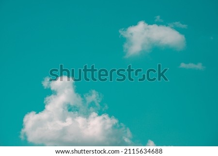 Photo of aqua blue sky with a group of white clouds in hard light contrast background. Abstract pop art photo of a surrealistic clean sky. Copy space artwork backdrop design awesome nature concept.
