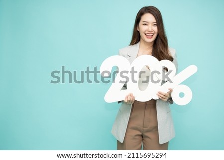 Portrait of Asian business woman holding 20% number or twenty percent isolated over green background Royalty-Free Stock Photo #2115695294