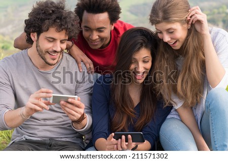 Group Of Laughing Friends With Cellphone Outdoor Royalty-Free Stock Photo #211571302