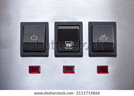 Black coffee brew button with drink cup symbol, close-up of panel with black plastic buttons for espresso coffee machine and heat steam for milk frothing.