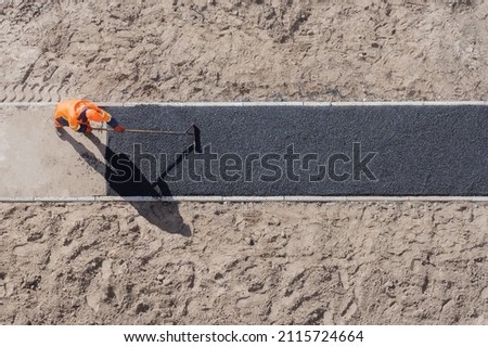 Laying worker new asphalt paving road construction site work pathway. New road construction worker laying asphalt surface on walkway work path. Sidewalk construction asphalt work tarmac road worker Royalty-Free Stock Photo #2115724664