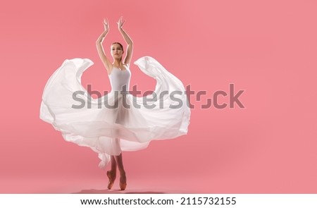 elegant ballerina in pointe shoes dancing in a long white skirt on pink background
