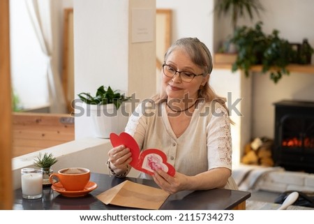 Elderly woman reads a message in a valentine Royalty-Free Stock Photo #2115734273