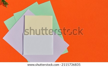 Creative concept for congratulatory letter, greeting card template. Horizontal layout with copy space. Postcard mockup with white envelope and multi-colored writing paper on an orange burnt background