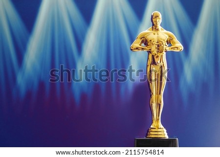 Hollywood Golden Oscar Academy award statue on light rays on black background with copy space. Success and victory concept. Royalty-Free Stock Photo #2115754814