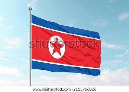 National flag of North Korea
 on a flagpole in front of blue sky