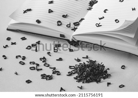letters of the alphabet fall out of the notebook, black and white shot, concept or idea of ​​a new book, article, copyright