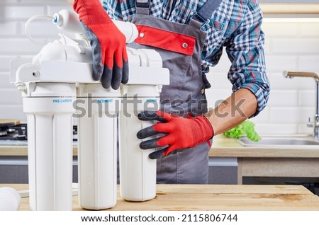 Plumber installs or change water filter. Replacement aqua filter. Repairman installing water filter cartridges in a kitchen. Installation of reverse osmosis water purification system.
 Royalty-Free Stock Photo #2115806744