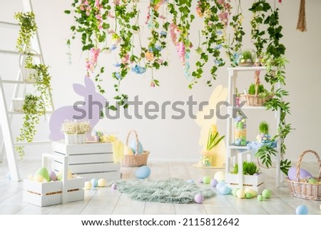 Backdrop for photo studio with easter design interior decorations for kids and family photo sessions. Plants, flowers, wooden rabbit, colorful dyed eggs, baskets.  Royalty-Free Stock Photo #2115812642