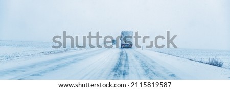 Freight transportation truck on the road in snow storm blizzard, bad weather conditions for transportation event, selective focus Royalty-Free Stock Photo #2115819587