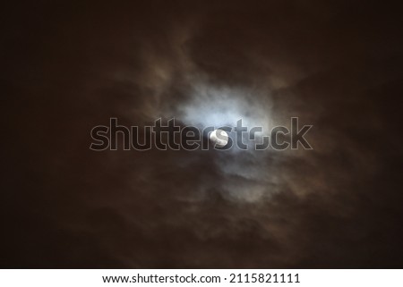 A picturesque landscape of the night sky with a full moon illuminating brown clouds with moonlight