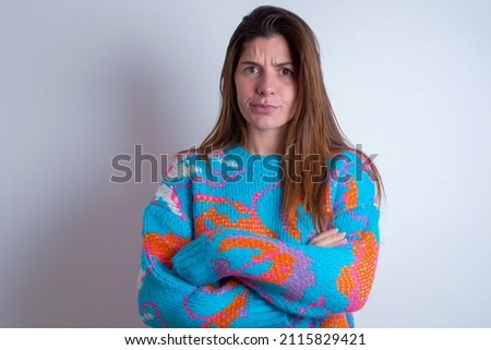 Young caucasian woman wearing vintage colorful sweater over white background Pointing down with fingers showing advertisement, surprised face and open mouth