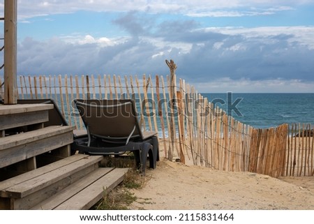 View of the Atlantic Ocean in Soulac sur Mer, France with a fence and furniture in the foreground