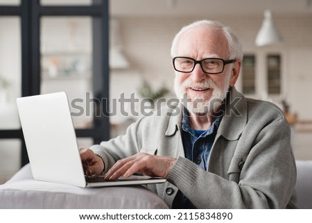 E-banking concept. Senior old elderly caucasian grandfather man using laptop for freelance work, checking pension, working remotely, surfing social media online relaxing on the sofa Royalty-Free Stock Photo #2115834890