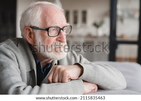 Lonely missing old people, senior man elderly grandfather sitting on the sofa, feeling pain, sick, ill, nostalgy, fraud, bankruptcy at home alone, needing help. Royalty-Free Stock Photo #2115835463