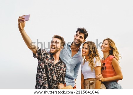 reunion gathering of generation z people having fun taking smartphone's selfie outdoors - isolated on white sky background - vacation and summer friendship carefree concept - vivid color filter