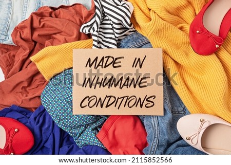 Fast fashion background with pile of cheap, low quality clothes. Garment made in unjust, inhumane conditions idea. Environmental impact, carbon emissions concept Royalty-Free Stock Photo #2115852566